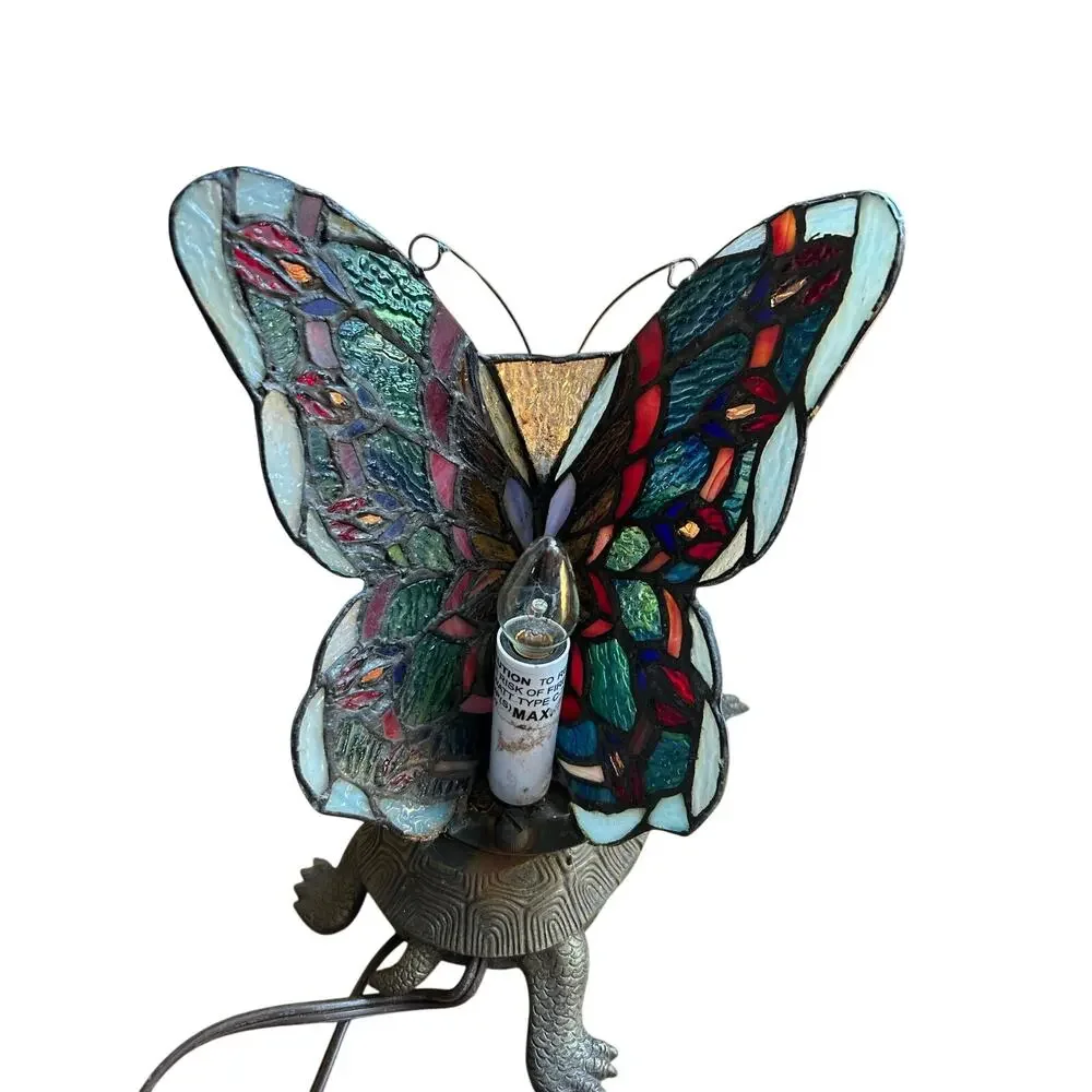 Vintage Tiffany style stained glass butterfly lamp resting on a brass turtle